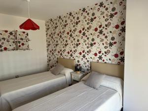 two beds in a room with floral wallpaper at Casa Emma in Burriana