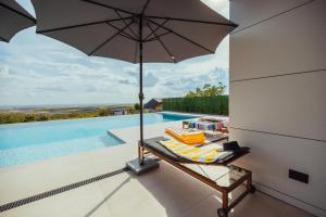 a chair with an umbrella next to a swimming pool at Vila Pogled in Vrdnik +20 photos