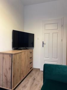 una sala de estar con TV de pantalla plana en una cómoda de madera en Pretty Room Centrum, en Suwałki