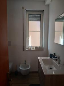 Un baño con lavabo, inodoro y ventana. en Casa Dormio, en Monopoli