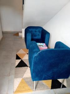 a living room with a blue chair and a rug at Iknews Appart Dakar in Kammba +1 photo