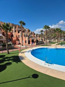 a swimming pool at a resort with palm trees and buildings at S&H La Malcriada in San Juan de los Terreros