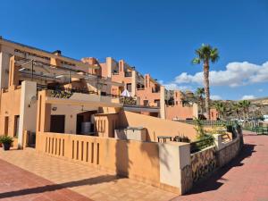 a building with a fence and a palm tree at S&H La Malcriada in San Juan de los Terreros