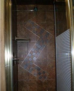 a shower with a glass door with a tile wall at Clearview Station & Caboose B&B in Creemore