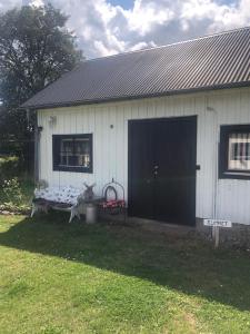 a white house with a black door and a bench at Hönshuset in Köpingsvik