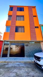 un edificio naranja con un coche aparcado delante de él en Miranda's House, en Puerto Chicama