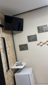 a room with a tv on the wall and a refrigerator at Pousada Três Corações in Penha
