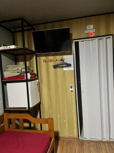 a room with a tv and a closet with a door at Pousada Três Corações in Penha