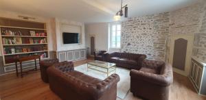a living room with leather furniture and a stone wall at Gîte château d'Espalungue, piscine et SPA in Dognen