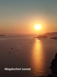 a sunset over the ocean with boats in the water at Aidos Villa Santorini in Megalokhori