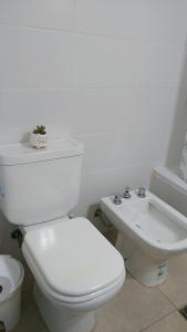 a white bathroom with a toilet and a sink at Casa Fiorella in Ezeiza