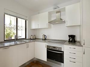 a kitchen with white cabinets and a sink and a stove at Sao Rafael Holidays in Albufeira