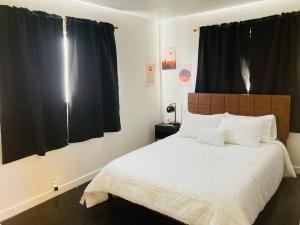 a bedroom with a large white bed with black curtains at 1940s Urban charmer modern upgrades in Auburn
