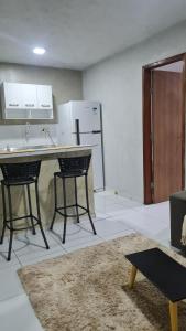 a kitchen with a counter and two stools in a room at Apartamento central in Natal