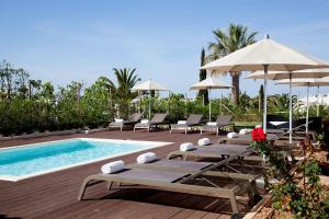 a pool with chaise lounges and chairs next to a swimming pool at Sao Rafael Holidays in Albufeira