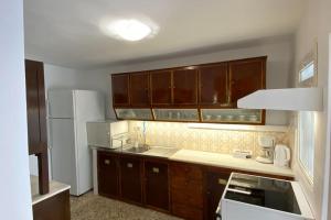 a kitchen with brown cabinets and a white refrigerator at Bee Home - Holiday Cottage in Agia Effimia