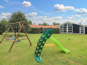a playground with a slide and a swing set at 14 person holiday home in Væggerløse-By Traum in Marielyst
