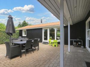 a patio with a table and chairs and an umbrella at 14 person holiday home in Væggerløse-By Traum in Marielyst
