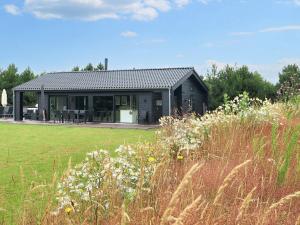 a black house with a grassy field in front of it at 9 person holiday home in Væggerløse-By Traum in Marielyst
