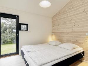 a bedroom with a large bed with a wooden wall at 9 person holiday home in Væggerløse-By Traum in Marielyst