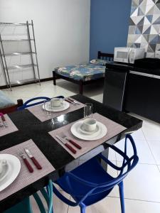 een tafel met twee stoelen en een tafel met borden erop bij Flats e Apartamentos Temporada Mar Brasil in Ubatuba