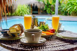 a table with a breakfast of fruit and orange juice at Ecolodge Spa Beira Mar Ococoloco in Porto De Galinhas