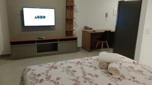 a bedroom with a tv and a bed with towels at Studio 608 in Marília