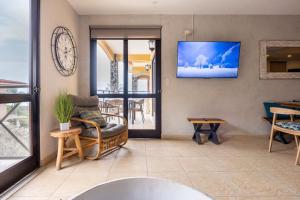 a living room with a couch and a tv on the wall at Jaco Beachfront Oasis Newly renovated dream condo in Jacó