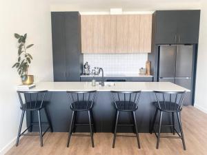 a kitchen with a counter and three bar stools at Luxe Loft - Inner City - Napier in Napier +24 photos