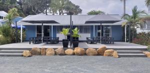 a blue building with a bunch of rocks and umbrellas at Hihi Beach Holiday Park in Mangonui