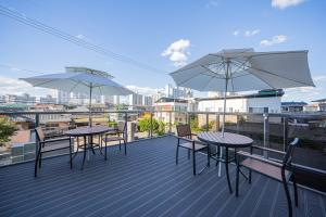 two tables and chairs on a balcony with umbrellas at Brown Dot Hotel Sangju in Sangju