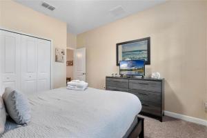 a bedroom with a bed and a dresser with a tv at Experience Solterra: Pool, Spa, Game Room & Lazy River in Davenport