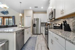 a kitchen with white cabinets and a stainless steel refrigerator at Experience Solterra: Pool, Spa, Game Room & Lazy River in Davenport