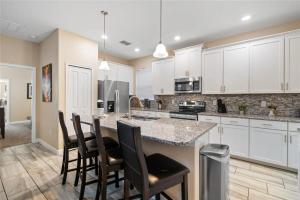 a kitchen with white cabinets and a island with bar stools at Experience Solterra: Pool, Spa, Game Room & Lazy River in Davenport