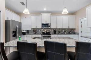a kitchen with white cabinets and a kitchen island with chairs at Experience Solterra: Pool, Spa, Game Room & Lazy River in Davenport