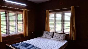 a bedroom with a bed and two windows at Ashiana Farms in Andevanahalli