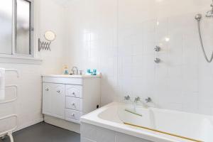 un bagno bianco con vasca e lavandino di Park Rise Cottage a Busselton Altre 25 foto