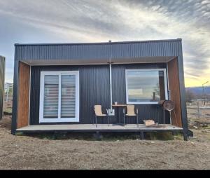 ein kleines Haus mit einem Tisch und zwei Stühlen in der Unterkunft Cabañas Campestres Altos de Leñadura Punta Arenas in Punta Arenas