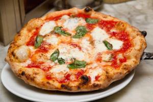 a pizza sitting on a plate on a table at B&B da Maria & Renato il Lago Trattoria in Mirabella Eclano +38 photos