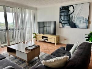 a living room with a couch and a flat screen tv at Sandbar unit 402 in Forster