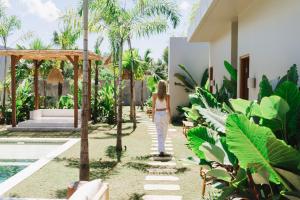a woman walking down a path next to a villa at Alma Bingin Boutique Hotel in Uluwatu