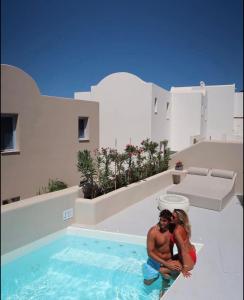 a man and a woman standing in a swimming pool at Pink Freud Villas Santorini in Oia