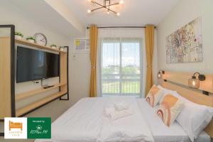 a bedroom with a bed with a tv and a window at RcplacePH T3-413- Pinesuites Tagaytay in Tagaytay +14 photos
