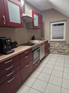 eine Küche mit roten Schränken und einer Arbeitsplatte in der Unterkunft Ferienwohnung Schusi Kesselsdorf in Kesselsdorf