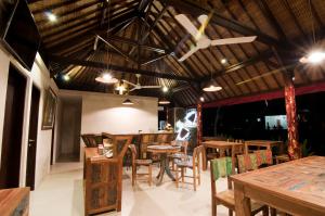 a restaurant with wooden tables and chairs and a ceiling at Villa Puspa in Tanah Lot