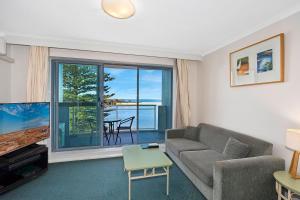 Una sala de estar con un sofá y una ventana grande. en The Entrance Waterfont Apartment 303, en The Entrance