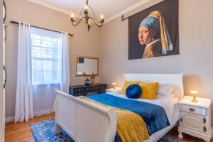 a bedroom with a bed with a painting on the wall at Blue Bell in Hermanus