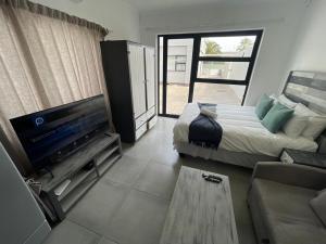 a bedroom with a bed and a tv and a couch at Fischreiher Seaside Self Catering Studio Apartment in Swakopmund