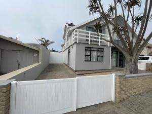 a white fence in front of a white house at Fischreiher Seaside Self Catering Studio Apartment in Swakopmund
