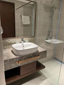 a bathroom with a white sink and a shower at APEC MANDALA CHAMBAY Thanh La Home in Phan Thiet